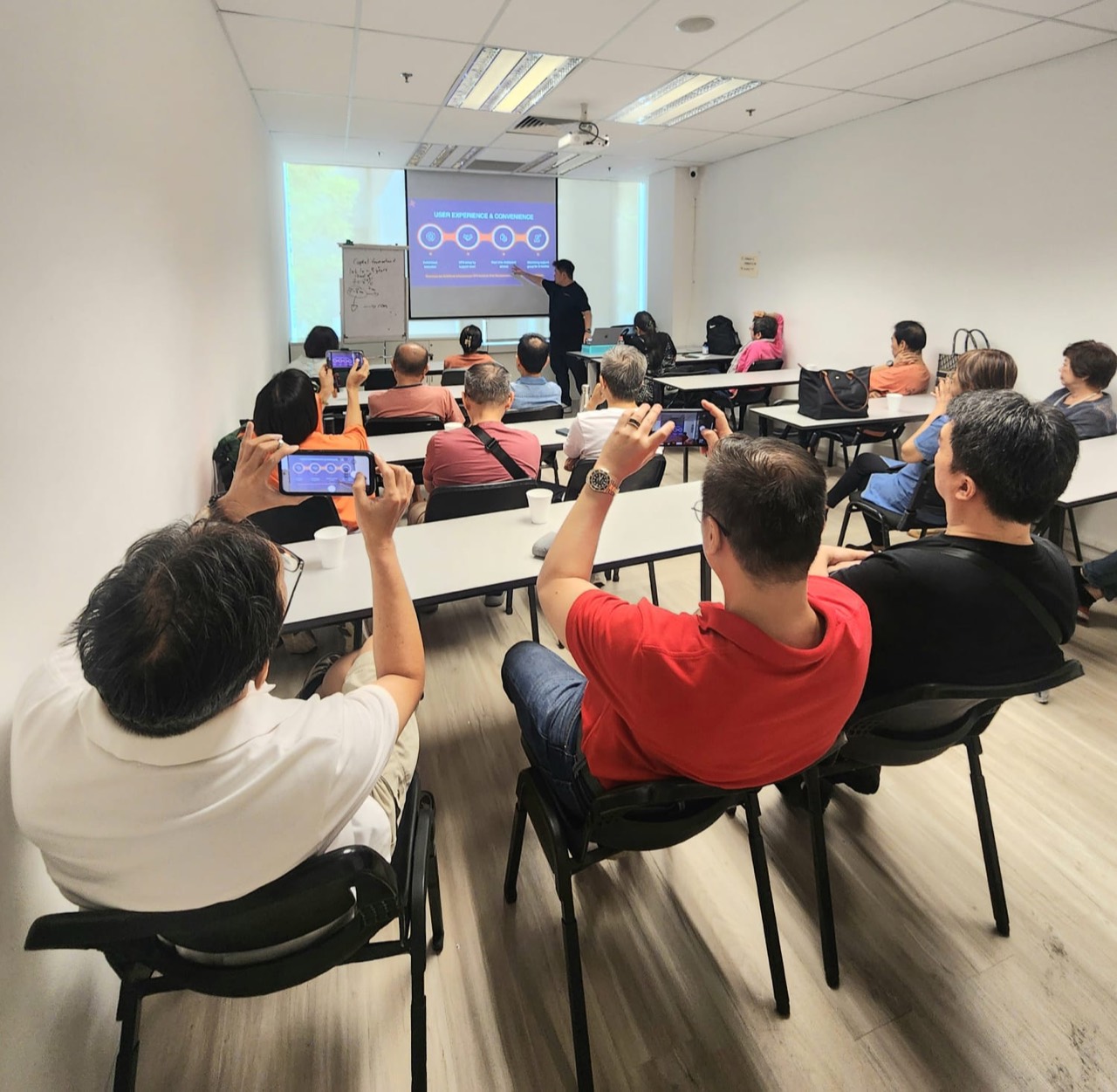 Trading technology workshop with attendees recording the presentation
